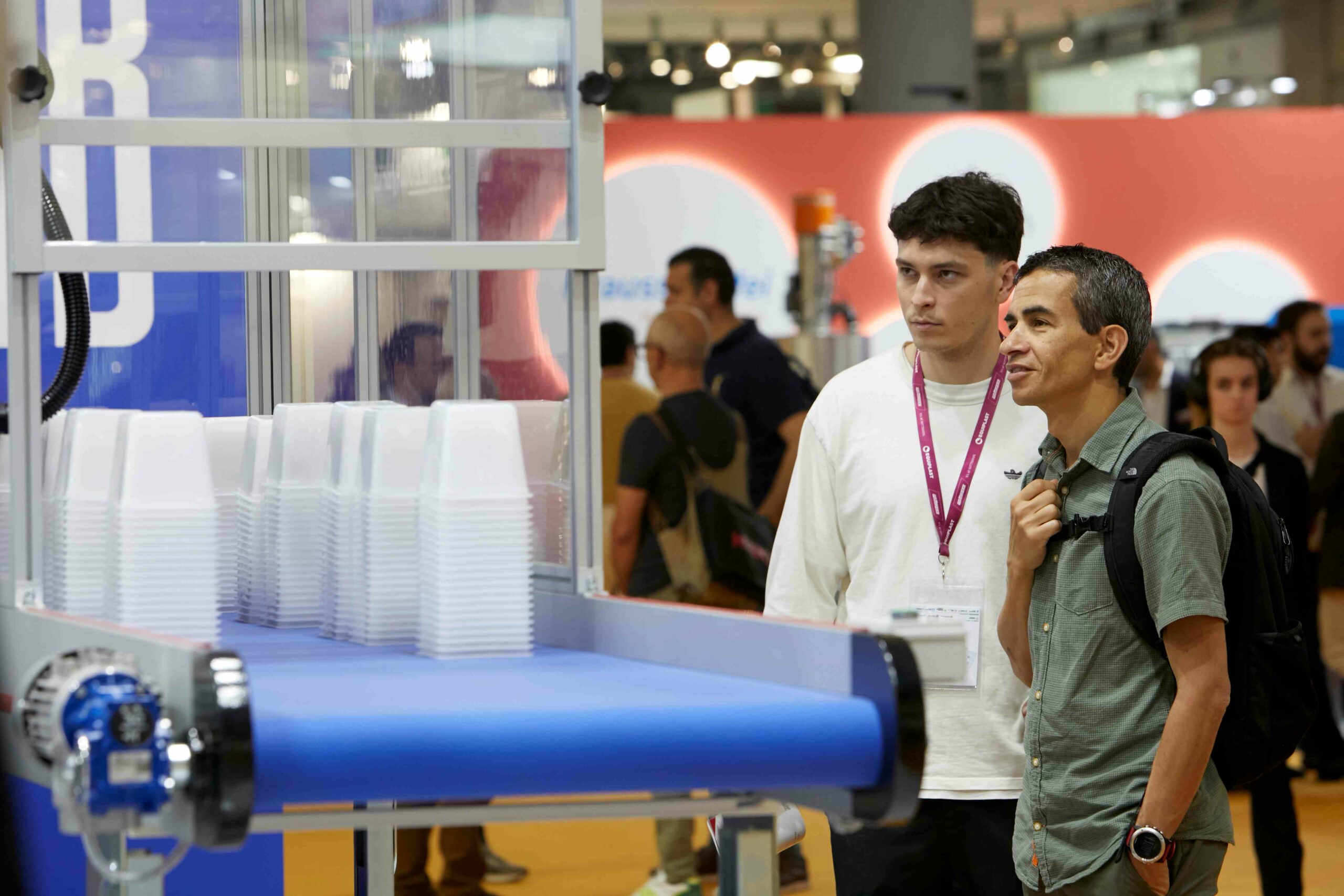 Dos personas miran una máquina transformadora de plástico expuesta en Equiplast 2023