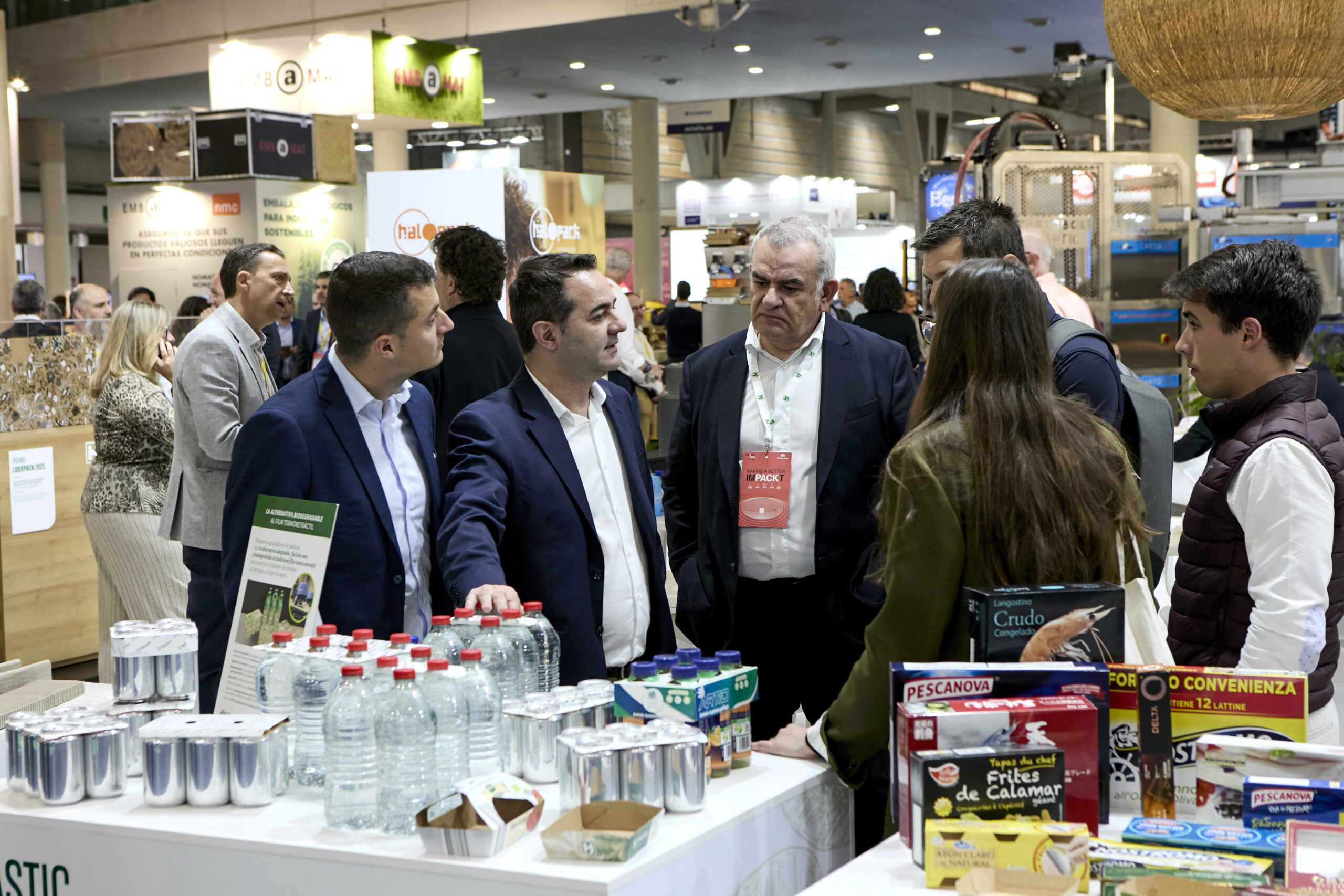 Stand en Hispack con visitantes y envases de diferentes tipos en primer plano