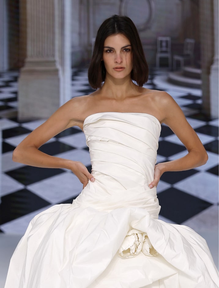 Modelo luciendo un vestido de novia sin tirantes, con un diseño elegante y detalles delicados.