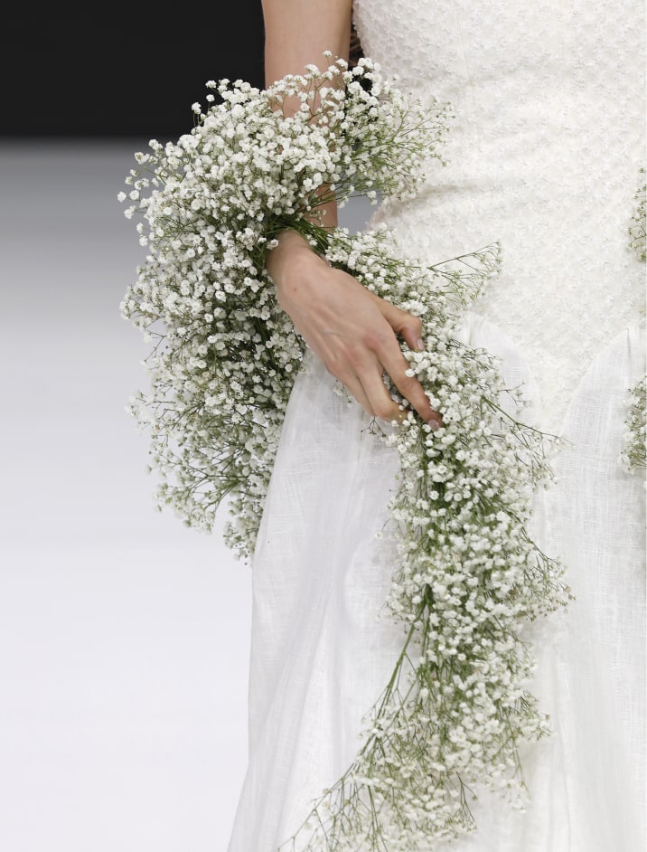 Detalle de vestido de novia sosteniendo un ramo de flores