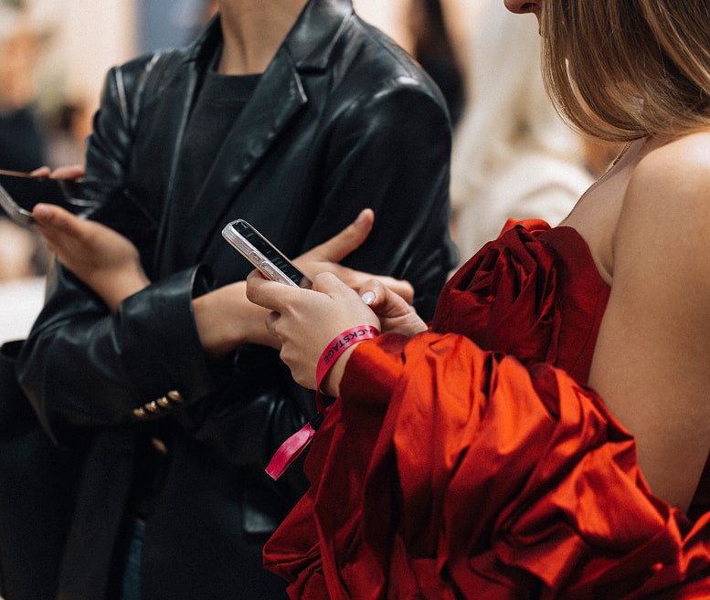 Dos mujeres con vestidos rojos mirando sus teléfonos móviles, concentradas en la pantalla