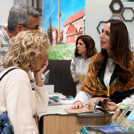 Expositora interactuando con visitantes y ofreciendo información sobre el salón.
