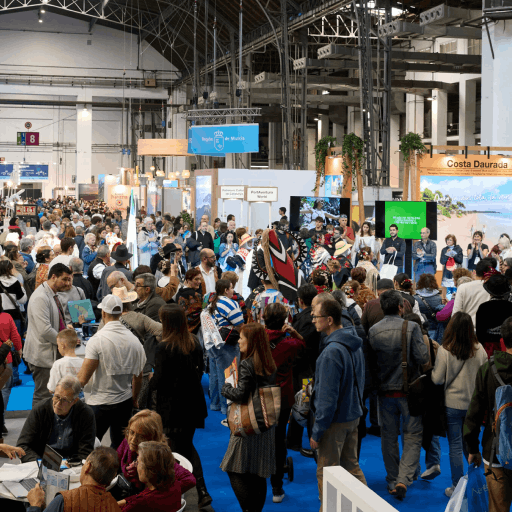 Gran afluencia de visitantes en el salón de B-Travel, con diversos estands de expositores visibles en el fondo.