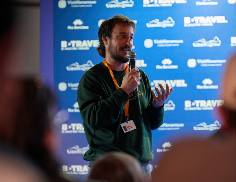 Hombre hablando en un micrófono durante una charla en el salón de B-Travel.